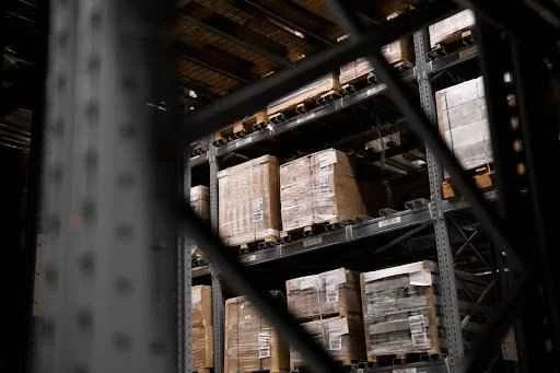 Warehouse shelves filled with stacked pallets, showcasing optimized space for customized storage solutions in a business environment.