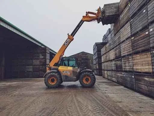 Forklift lifting wooden pallets in a storage area, illustrating equipment use in material handling and logistics.