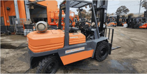 Forklift with Toyota branding, showcasing a robust design, parked in an industrial setting surrounded by additional forklifts, symbolizing the importance of forklift accessories for operational efficiency and equipment longevity.