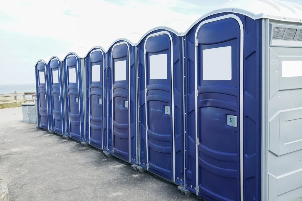Row of blue portable toilets designed for construction sites, featuring reinforced frames for safety and accessibility, suitable for high-rise locations, emphasizing hygiene and compliance with regulations.
