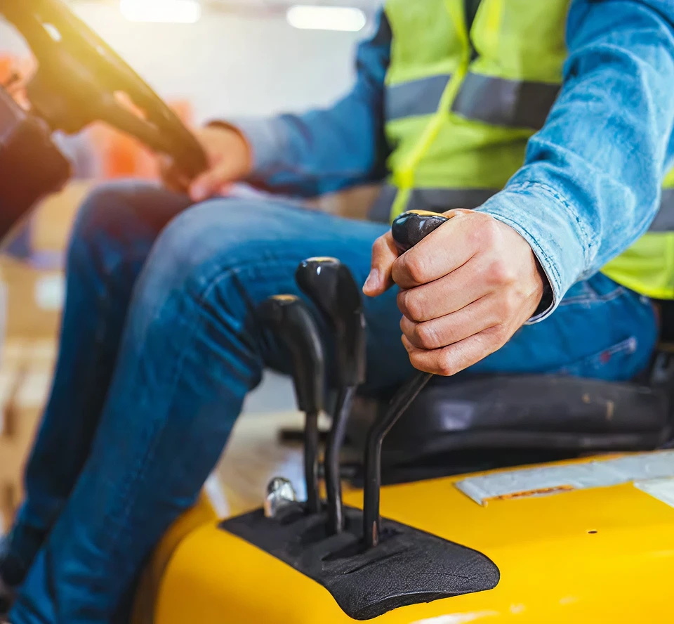 Operator in safety vest using gear lever on forklift, emphasizing transmission control and machinery operation.