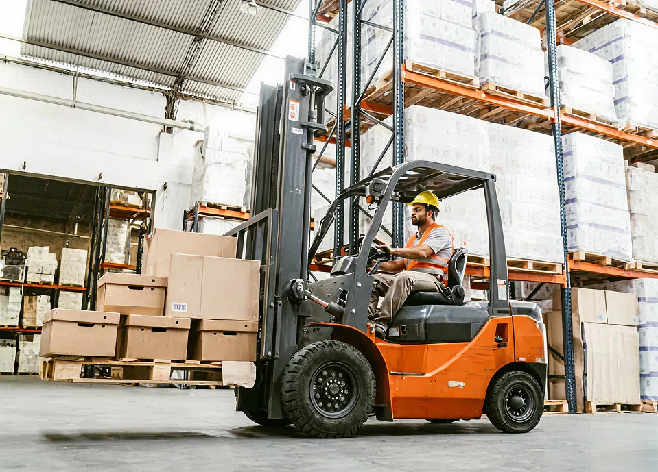 Forklift operator maneuvering boxes in a warehouse, demonstrating efficient material handling for industrial applications.