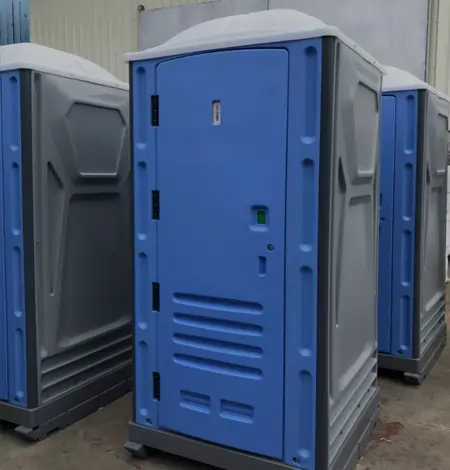 Portable toilet units in a row, featuring a blue exterior and grey accents, showcasing durable worksite equipment for industrial and warehouse solutions.